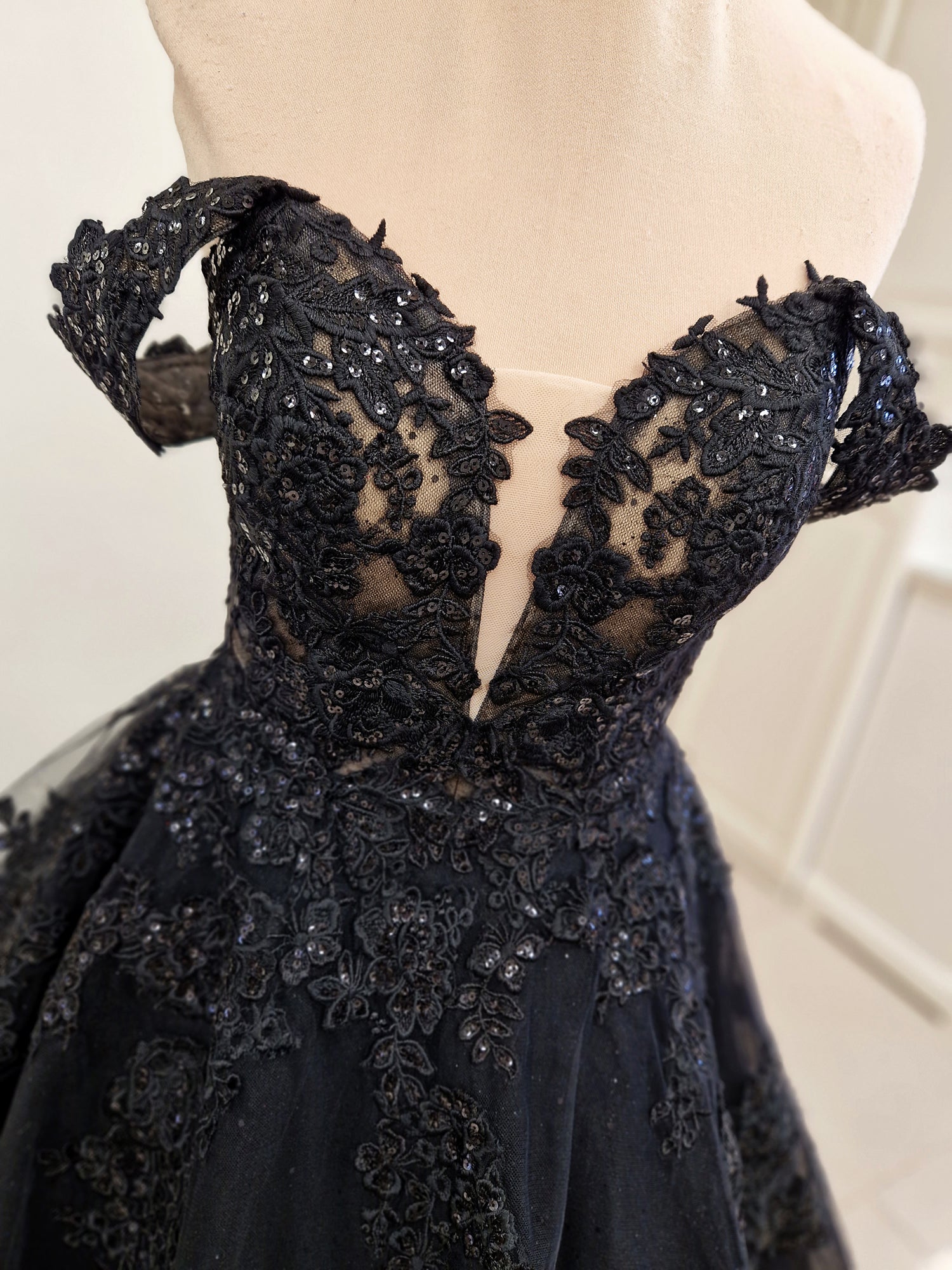 Black wedding dress in ball gown silhouette with deep plunging sweetheart neckline, detachable off-shoulder straps and semi-sheer corset bodice.