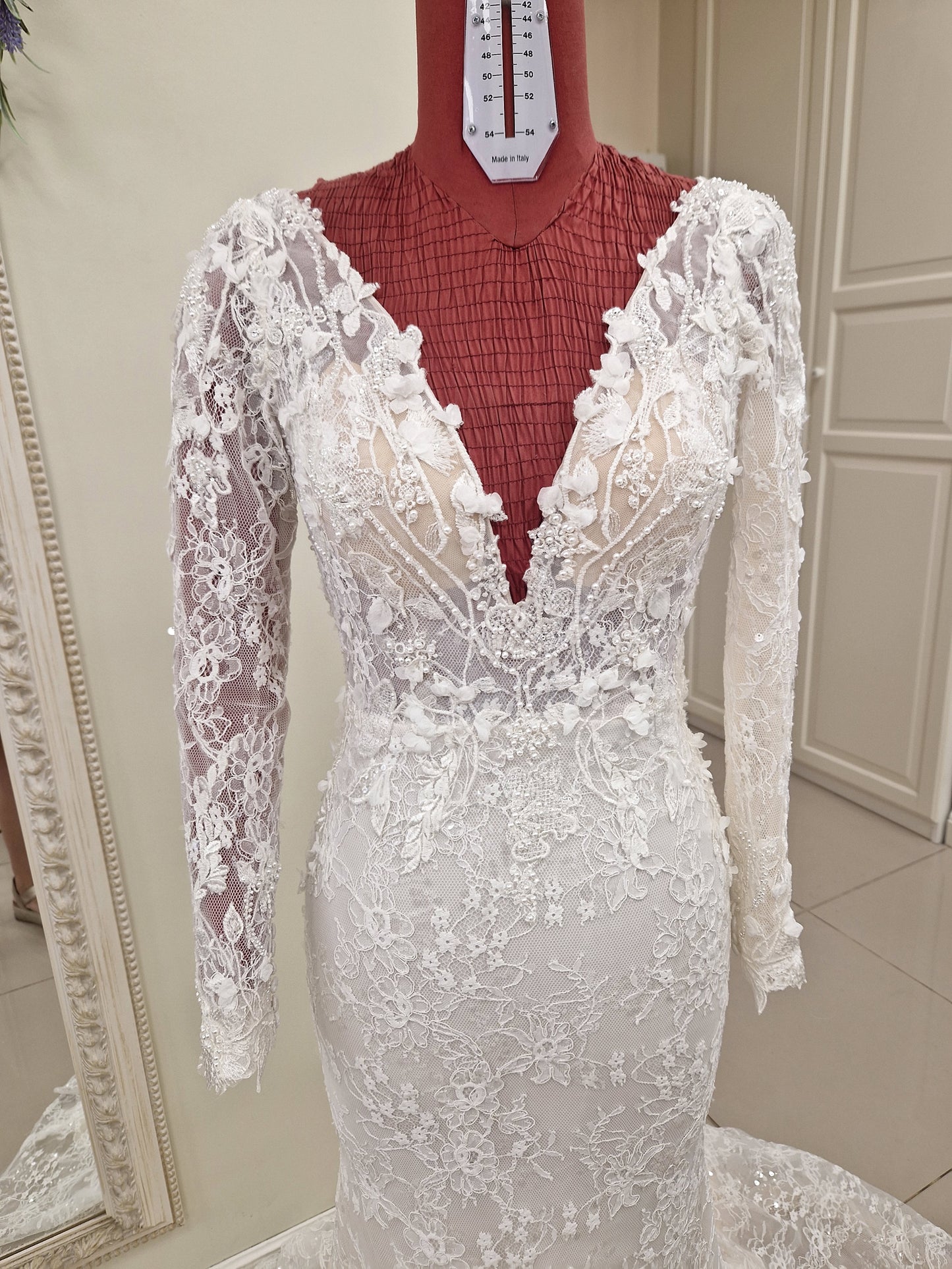 Lace wedding dress from our 2024 couture collection. The gown has a figure hugging trumpet silhouette, long sleeves, deep plunging V-neckline and V-back and lots of beading and sparkle.